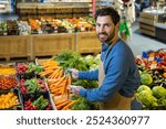 Grocery worker arranging fresh vegetables at supermarket, smiling while handling carrots. Surrounded by vibrant produce like tomatoes, radishes, and lettuce. Represents healthy eating