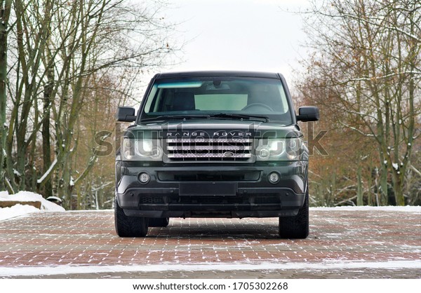 Grodno, Belarus,\
December 2012: Land Rover Range Rover Sport V8 Supercharged. Front\
view of black SUV over out of focus winter forect background with\
copy space.