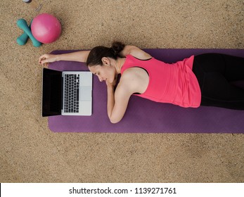 Groggy Woman Sleeping Infront Of A Laptop On A Yoga Mat After  Doing A Fitness Workout From Bird View