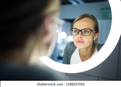 Groggy, Young Woman Checking Her Make-up In Front Of Her Bathroom Mirror In The Morning - Trying To Wake Up And Get Ready For Work (color Toned Image; Shallow DOF)