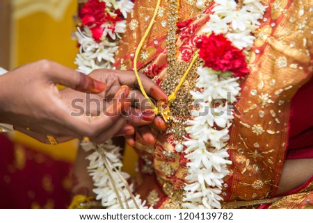 The groom add red powder to the wedding necklace (Thali) of the bride.
