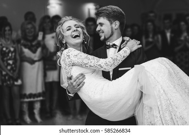 Groom admires happy bride laughing in his arms