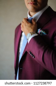 The groom arranges his blue tie, close view whith background