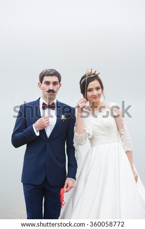 groom attached to the face paper mustaches and bride put to her  head a crown Valentines Day