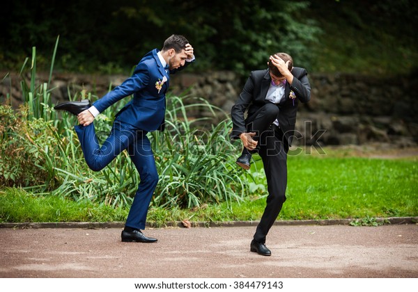 Groom and bestman dancing and goofing around\
after wedding ceremony in the\
park