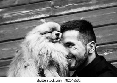 The Groom In A Black Suit Is Holding A Small Pug Dog In His Hands