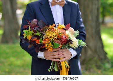 The Groom In A Blue Suit Holding A Autumn Wedding Bouquet