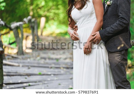 Groom and bride cropped image. Unrecognizable woman in wedding dress with man stand outdoors in summer park, shoot made with copy space. Happy couple