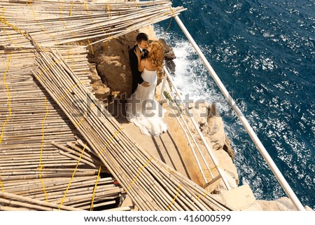 groom and bride kissing near the sea