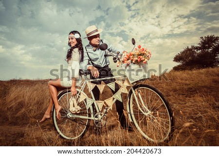 Groom and bride on a bicycle with just married sign and cans attached