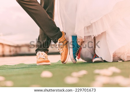 groom and bride in plimsolls on green carpet