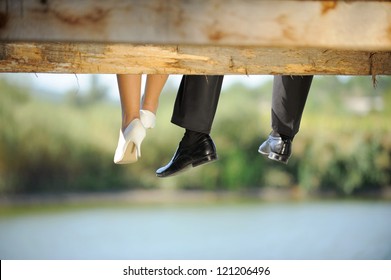 groom and bride sitting on bridge