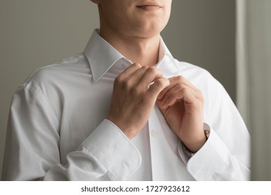 the groom buttons a button on his shirt, man in a white shirt, wedding day - Powered by Shutterstock