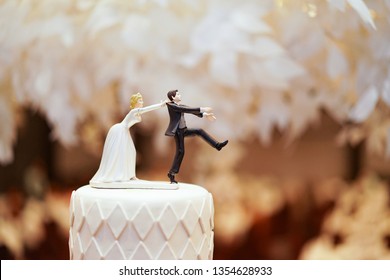 groom doll and statue is running away but bride can catch him finally. the funny wedding story doll on the top of cake.