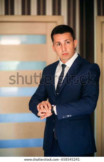 The groom is dressed at home in a suit. Cute groom posing for a photographer. spring