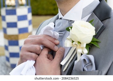 The groom is fixing his tie outside
