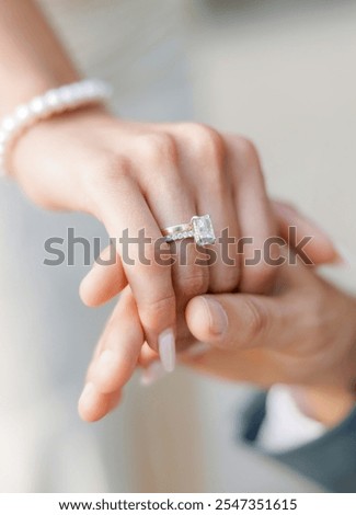 The groom gently holds the hand of the bride with a wedding ring. Hands of the bride and groom close-up. A wedding ring with a large gemstone is worn on the bride's hand