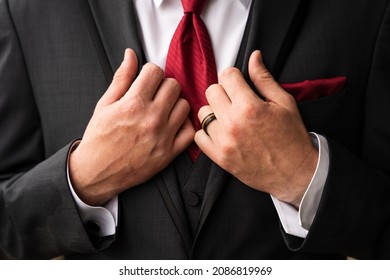 Groom Getting Ready With A Red Tie, His Wedding Band, Red Pocket Square, And Cufflinks