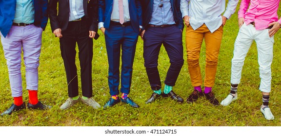 Groom and groomsmen in colored socks stand on the green grass