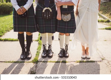 Groom And Groomsmen Wearing Scottish Traditional Kilt And Bride In White Dress