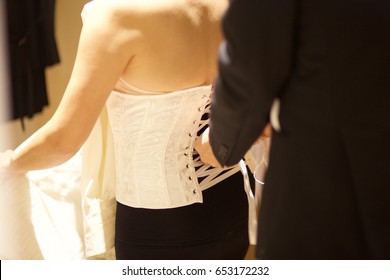 Groom Hand Lace Up Corset On Bride's Delicate Waist.Selective Focus At Corset.