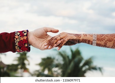 Groom holds tender hand of Hindu bride covered with henna tattoo