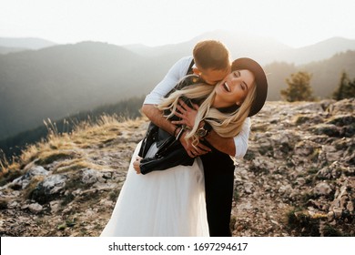 groom hugging his bride and kissing her neck and she is laughing. mountains on background. - Powered by Shutterstock