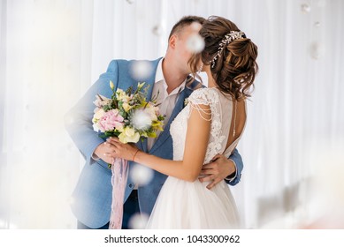 The groom kisses the bride in the room