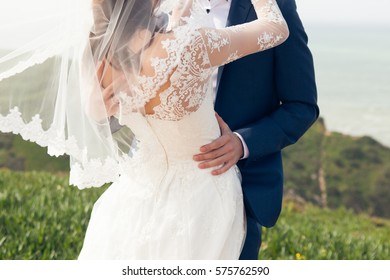 Groom kissing the bride in a wedding dress an oceanfront - Powered by Shutterstock