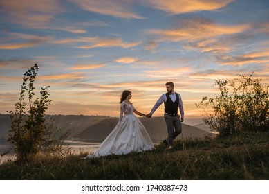 The groom leads the bride by the hand during sunset. - Powered by Shutterstock