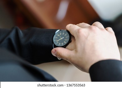 Der Bräutigam sieht auf seine Uhr, um die Zeit zu überprüfen. Die Uhr ist auf der Hand des Mannes getragen.