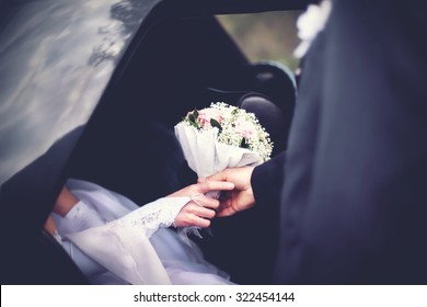 Groom meets the bride from the car with a wedding bouquet of flowers