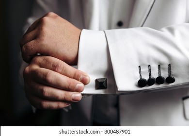 groom in the morning on the wedding day buttoning cuffs his hands on his suit