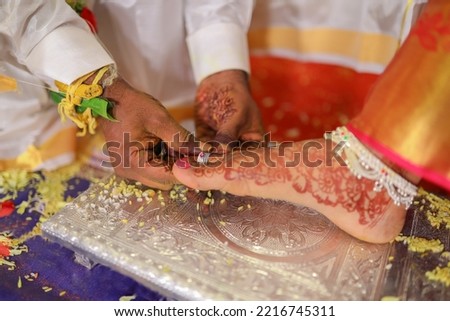 The groom puts a toe ring for the bride during a Hindu wedding. 