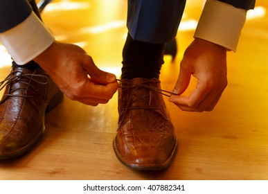 Groom Putting On Brown  Wedding Shoes At Home