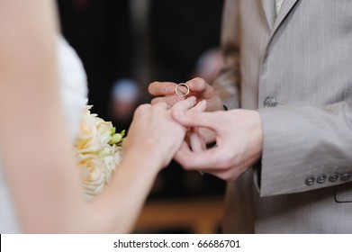 Groom Putting A Wedding Ring On Bride's Finger