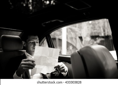 Groom Reads His Wedding Speech Sitting On The Back Seat In The Car