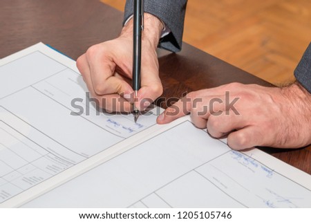 The groom signing registration of marriage certificate in wedding ceremony. Close up.