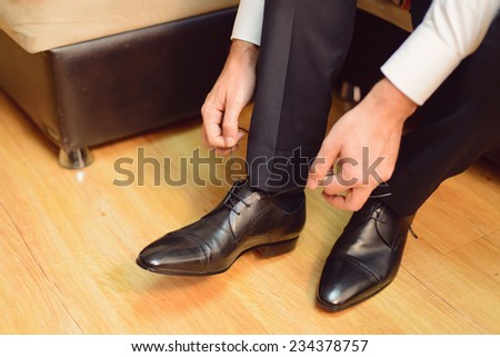 groom straining laces on wedding shoes