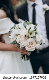 the groom in a suit and the bride with a bouquet of flowers are standing next to each other