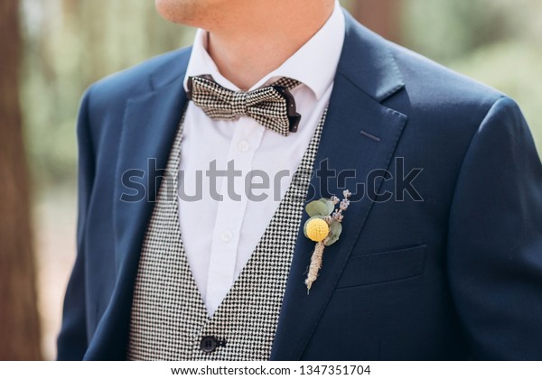 the\
groom in a suit straightens his tie bubochku. boutonniere on the\
lapel of his jacket. young man in a business\
suit.