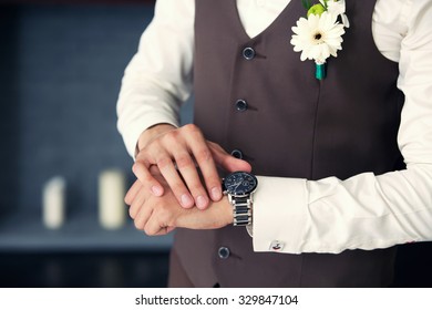 the groom in a waistcoat looks at the clock in the room - Powered by Shutterstock