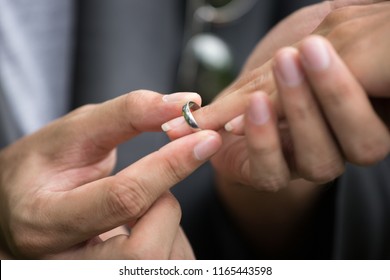 The groom is wearing a ring for the bride. It is a promise to have each other forever. - Shutterstock ID 1165443598