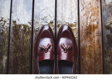 Groom wedding details. Leather shoes on wooden background with raindrops