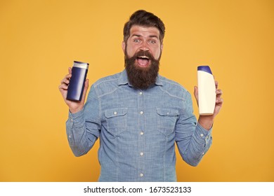 Grooming At Every Opportunity. Bearded Man Hold Shampoo Bottles Yellow Background. Cosmetics And Toiletries. Hygiene And Personal Grooming. Male Body Grooming And Skincare. Grooming Products For Men.