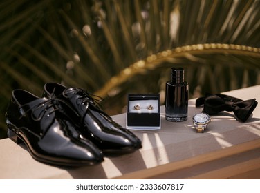 
Groom's shoes, perfume and cufflinks, watch, bow tie in the shade of palm leaves - Powered by Shutterstock