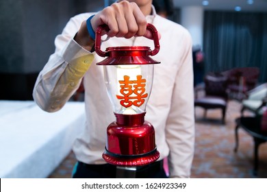 Groomsman Holding Red Traditional Lantern Lamp, With Chinese Character Stickers Meaning Double Happiness, In Chinese Wedding Ceremony As Appropriate For Marriage Gift. Symbol Of Male Childbearing.