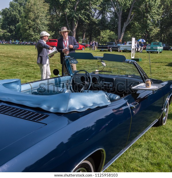 GROSSE POINTE\
SHORES, MI/USA - JUNE 17, 2018: Judges review a Chevrolet Corvair\
car at the EyesOn Design car show, held at the Edsel and Eleanor\
Ford House, near Detroit,\
Michigan.