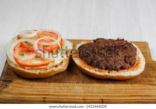 Ground beef burger with tomato, onion and\
lettuce, homemade.