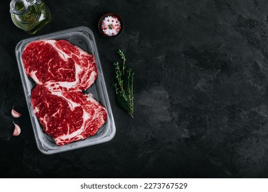 Ground Beef steak in vacuum packaging with seasonings on dark stone background, top view, copy space - Powered by Shutterstock